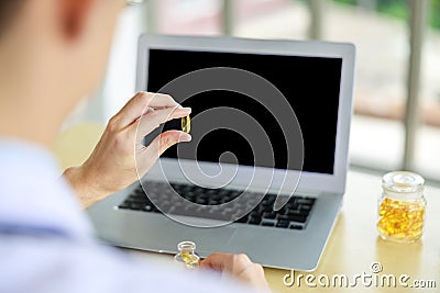 close up and silective focus rear viev doctor hands holding Omega-3 pills and laptop computor on the table in office , healthy Stock Photo