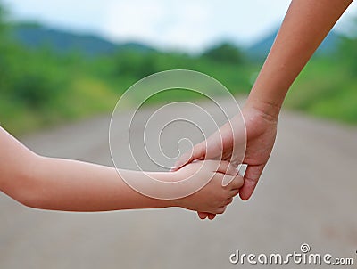 Close up of Sister hold hands with small children walking on the road Stock Photo