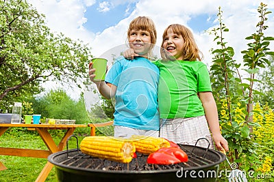 Close-up of sisters grilling corn with paprika Stock Photo