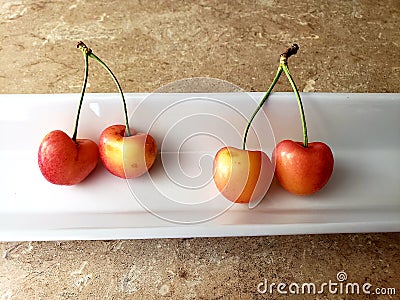 Close up on four paired up red and yellow cherries on a white plate Stock Photo