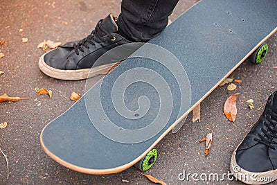 Close-up of a skateboarder`s foot in black sneakers. Stock Photo