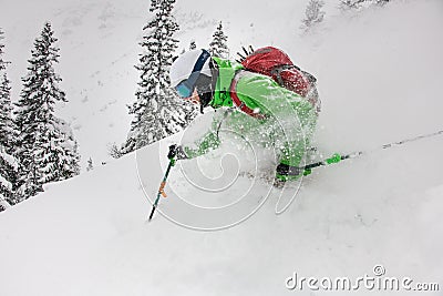 Close-up of skier descending a snow-covered slope and splash of snow around him Stock Photo