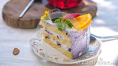 Close up Slice birthday fruit cake in plate violet delicious cream in layer Stock Photo