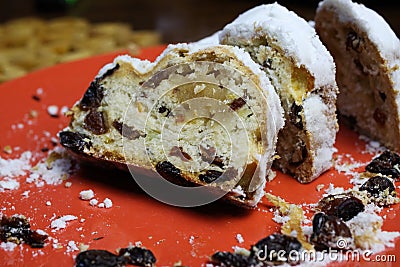 Close up of sliced christstollen with raisins, white powdered sugar and marzipan on red plate Stock Photo