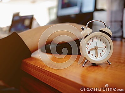 Close up small alarm clock with officer hand on the laptop Stock Photo