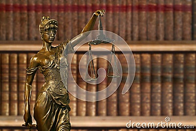 Small bronze statue of Lady Justice before a bookshelf Stock Photo