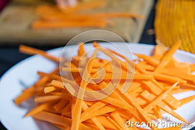 Pile of thin carrot slices on white plate with blurry background Stock Photo