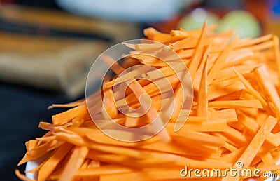 Pile of thin carrot slices on white plate with blurry background Stock Photo