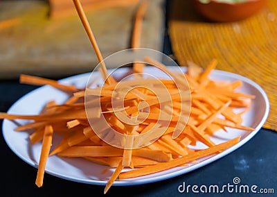 Pile of thin carrot slices on white plate with blurry background Stock Photo