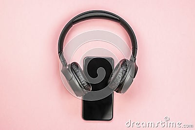 Close-up of smart phone with headphones on a pink background. Stock Photo