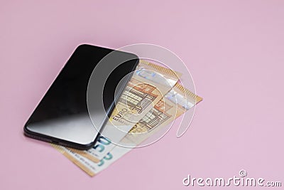 Close-up of smart phone with money on a pink background. Stock Photo