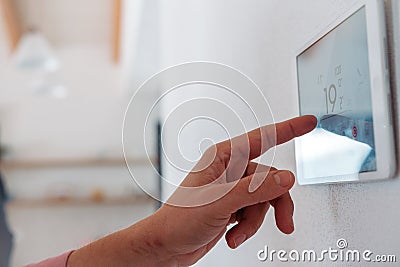 Close up of smart thermostat, adjusting, lowering heating temperature at home. Concept of sustainable, efficient, smart Stock Photo