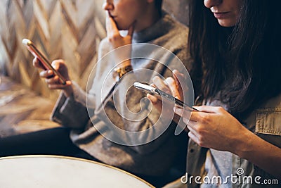 Close-up of smartphone in hands, meeting of two friends sitting at the table in cafe. Stock Photo