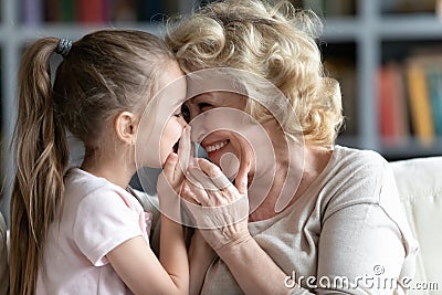 Close up smiling grandmother and little granddaughter talking, sharing secrets Stock Photo