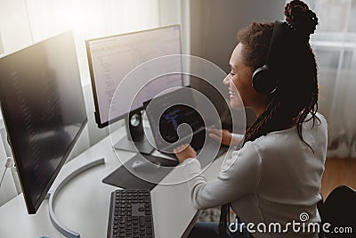 Close up of smiling mixed-race woman web expert programming on computer looking at monitors Stock Photo