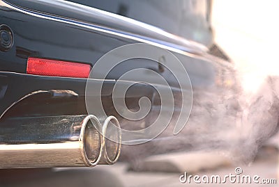 Close up of smoky dual exhaust pipes from a starting diesel car. Stock Photo