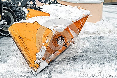 Close-up snowplow of big tractor machine removing and cleaning snow after storm on icy road or city street at alpine mountain Stock Photo