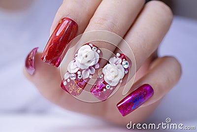 Close up sparkling red color gel polish painting beautiful 3D rose flower decorate d with shiny rhinestone and glitter on Stock Photo