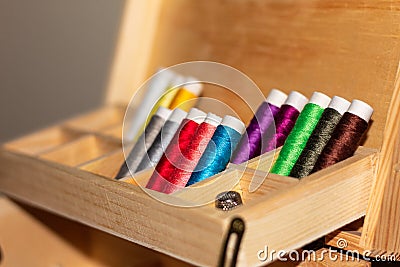 Close-up of spools of thread.with lots of color, inside a wooden sewing kit. Blue, red, yellow, green, purple Stock Photo