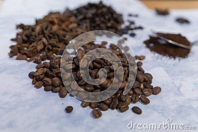 Spoonful of coffee surrounded by piles of coffee beans and star anise seeds Stock Photo