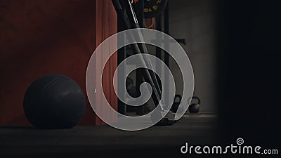 Close-up of sports equipment in gym. Black fitness ball and rod neck on background of kettlebells and dark walls of Stock Photo