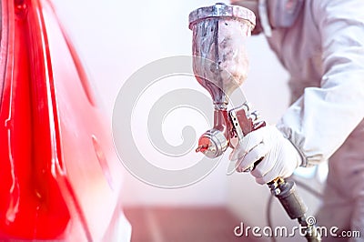 Close-up of spray gun with red paint painting a car Stock Photo