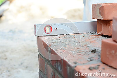 A close-up on a sprit level used to level the corner brick courses on a mortar bed while bricklaying the wall of the house Stock Photo