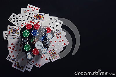 Close up stack of different colored poker chips, playing cards and dices isolated over black casino table background with copy Stock Photo