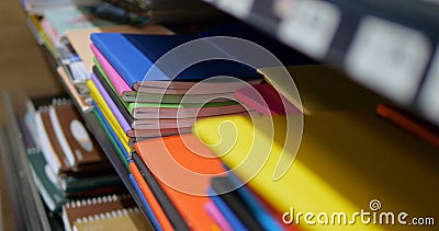 Close-up of stack of multicolored notebooks and exercise books on shelf in shop. Stock Photo