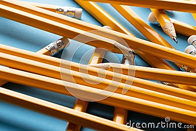 Close up of stack of yellow pencils with erasers on blue background Stock Photo