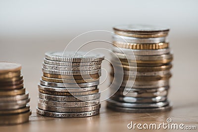 close up of stacks of coins on wooden tabletop Stock Photo