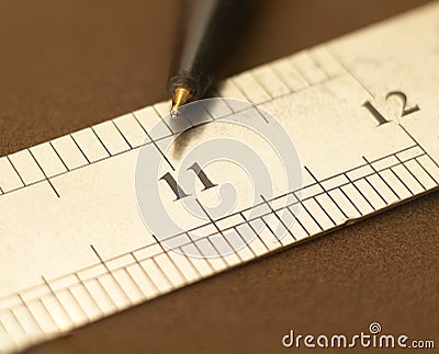 Close-up of a stainless steel scale ruler showing an eleven-inch point with a pen, Selective focus, isolated on Dark background Stock Photo