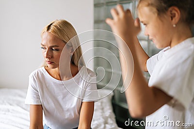 Close-up of standing aggressive little child daughter scolding, raising voice, shouting to sad depressed pensive young Stock Photo