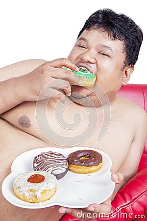 Close up of starving fat man eat donuts on studio Stock Photo