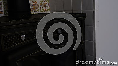 Close up of stove firewood heater inside apartment with white small tiles with animals and flowers behind. Creative. Old Stock Photo
