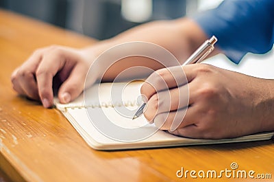 Close up of student hand writing on book with pen Stock Photo