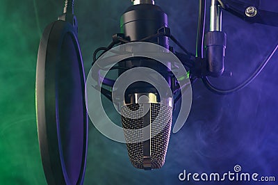 Close up studio condenser microphone on stand and anti-vibration mount. Live recording with colored lights background. Side view. Stock Photo