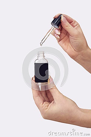 Close Up Studio Shot Of Woman Holding Bottle Of Essential Or Cannabis Oil With Dropper Stock Photo