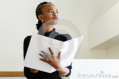 Close-up of successful African or black American business woman holding big white file and thinking Stock Photo