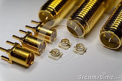 Close-up of symmetric aligned gold plated uFL, MMCX micro precision radio connector partial focus white SMA background Stock Photo