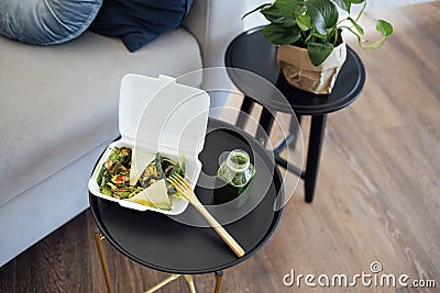 Close up of take away food in white container with wooden fork and plactic bottle of green smoothie Stock Photo