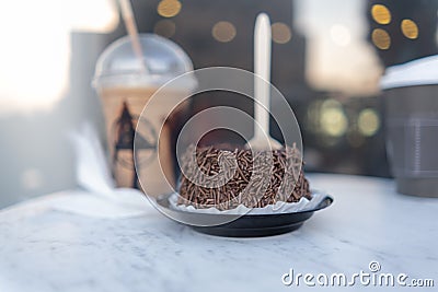 Frappuccino, small chocolate cake, and coffee cup on round gray table Stock Photo