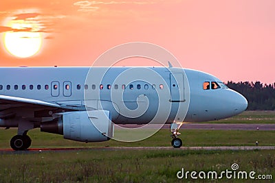 Close-up taxiing a white passenger airplane against the setting sun Stock Photo