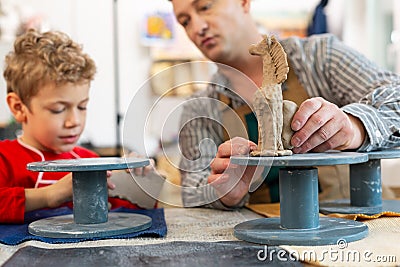Close up of teacher and student sculpting clay figures Stock Photo