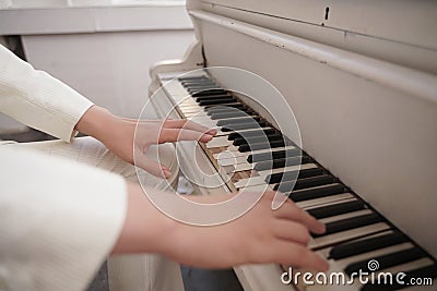 Close up of teenager arms with old white grand piano. person in white clothes plays music. Stock Photo