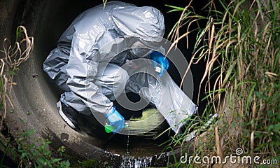 Close-up, the terrorist in a protective suit and gloves, pours liquid with poison, for infection, in a drainpipe Stock Photo