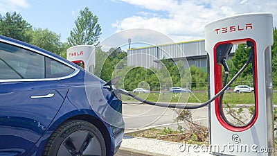 CLOSE UP: Tesla car with new Michelin tyres charges at the side of a highway Editorial Stock Photo