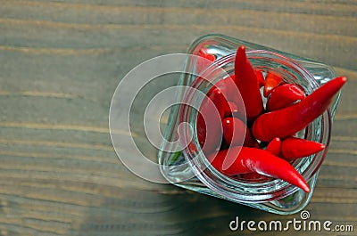 Close up of Thai red fresh hot chilli peppers in a glass vintage jar, blurred brown background. Food pattern. Popular spices Stock Photo