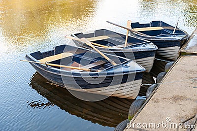 Close up of three blue and white rowing boats moored on a tranquil river on a sunny day Stock Photo