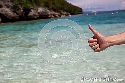 Close-up of thumbs up gesture in beach sea shore background. Stock Photo